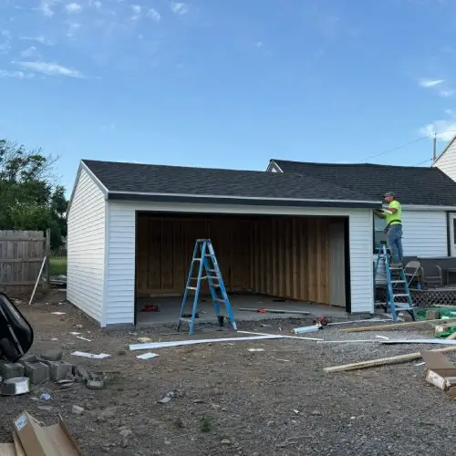 A new two-car garage addition featuring vinyl siding, a black shingle roof, and a custom build-out.